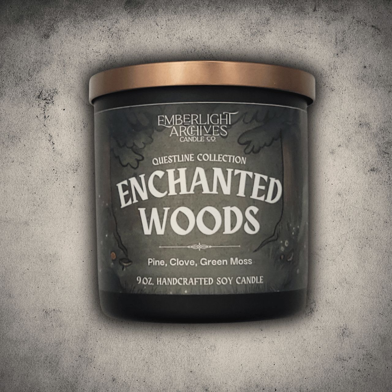 Emberlight Archives Enchanted Woods candle in a 9oz black glass jar with illustrated forest label against a gray stone background, Pine and Clove scent.
